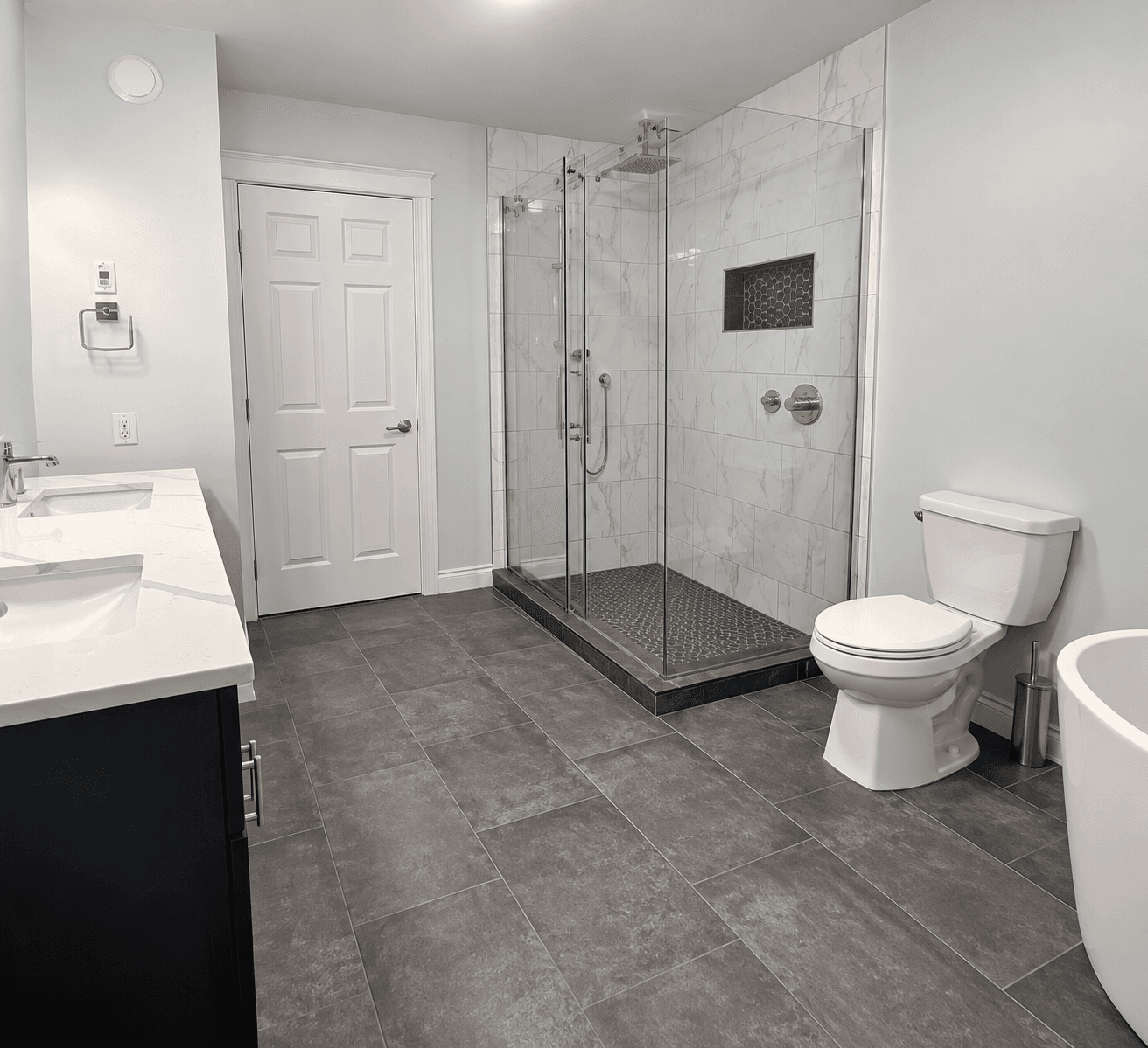 Finished basement bathroom with a glass-enclosed marble tile shower and freestanding tub